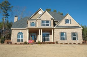 A blue and beige big house with an open house signage in front